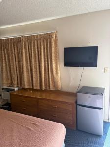 a hotel room with a television and a dresser with a dresser at Townhouse Motel- Alhambra-South Pasadena-San Marino in Alhambra