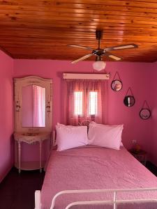 a pink bedroom with a bed and a ceiling fan at Krista's house in Agioi Theodoroi