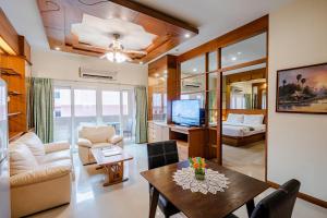 a living room with a table and a couch and a television at Whitehouse Condotel in Pattaya