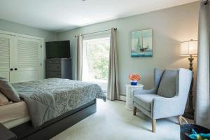a bedroom with a bed and a chair and a window at Tideview Estate in Cumberland Foreside
