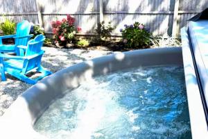 a hot tub in a yard with a blue chair at Salt & Petal in Old Orchard Beach