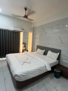 a bedroom with a large bed with white sheets at Infinity Hotel in Rajkot