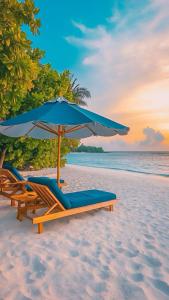 two lounge chairs and an umbrella on a beach at Handhuvaru Maldives in Milandu