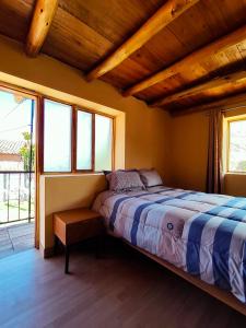 a bedroom with a bed in a room with windows at Casa Rumiwillka in Urubamba