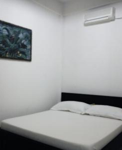 a white bed in a room with a picture on the wall at villa house luxury in Cianjur