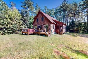 a small red house with a deck in a yard at Pinecone Lodge in Newry