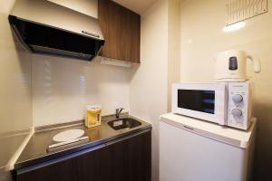 a small kitchen with a microwave and a refrigerator at 萩別邸 シーサイド1 HAGI Bettei SEASIDE1 in Hagi +3 photos
