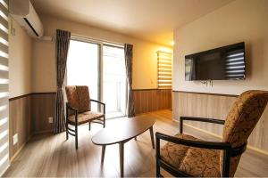 a living room with a table and chairs and a television at 萩別邸 シーサイド1 HAGI Bettei SEASIDE1 in Hagi