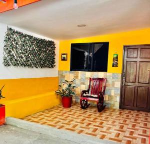 a yellow room with a rocking chair and a door at Apartamento El Almendro in Liberia