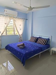 a bedroom with a bed with blue walls and a window at D'Nas Homestay in Rawang