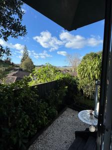 a view from the balcony of a garden with a table at Pōhutukawa Studio in Tauranga
