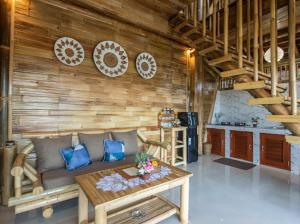 a living room with a couch and a wooden wall at Uma Bali-Bamboo House in Selat