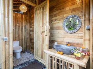 a wooden bathroom with a tub and a toilet at Uma Bali-Bamboo House in Selat +37 photos