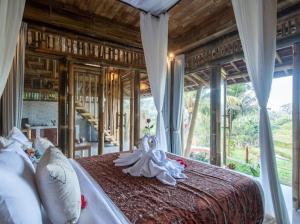 a bedroom with a large bed with a large window at Uma Bali-Bamboo House in Selat