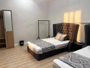 a bedroom with two beds and a headboard at Over lock in Buraydah