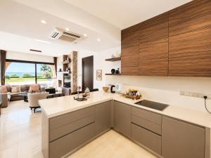 a kitchen with wooden cabinets and a living room at Emerald Seafront Residence in Ayia Napa