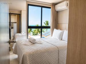 two beds in a room with a view of the ocean at Beachfront flat at Porto de Galinhas beach, close to the natural pools. in Porto De Galinhas +130 photos