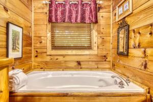 a bathroom with a tub in a cabin at Naughty Pines in Pigeon Forge +17 photos