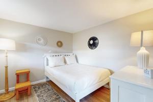 a white bedroom with a bed and a clock on the wall at Gull's Getaway in York