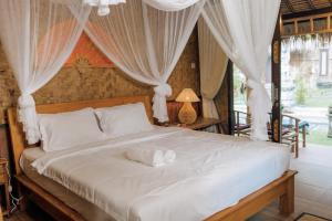 a bedroom with a large bed with white drapes at Pondok Sapta Sallaca in Selat