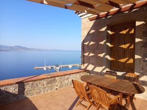 a wooden table and chairs on a patio overlooking the water at Villa Annie in Mythimna
