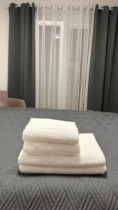 three white towels are stacked on a bed at Bella Vista Lux apartment in Baošići