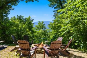 three chairs and a fire pit with a view at A Tree Top View home in Gatlinburg