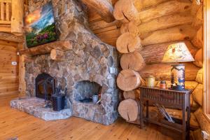 a living room with a stone fireplace in a log cabin at Buffalo Creek Lodge in West Jefferson +54 photos