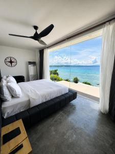 a bedroom with a bed and a large window with the ocean at Epic Suites Bohol ADULTS ONLY in Dauis +127 photos