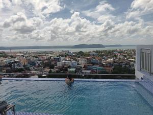 a person sitting in a swimming pool looking at a city at California style Resident in Iloilo City
