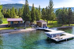a dock with a house and a boat on the water at The Meadowlark Cabin in Big Arm