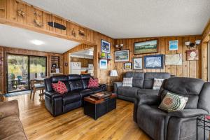 a living room with leather furniture and wooden walls at The Meadowlark Cabin in Big Arm
