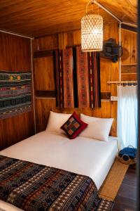 a bedroom with a white bed in a wooden room at Hihi Homestay Tả Van - Mountain View & Local Experience in Sa Pa in Tả Van