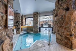 a pool in a room with a stone wall at Shoshone 1922 in Big Sky