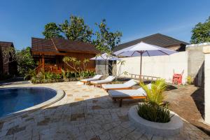 a patio with chairs and an umbrella next to a pool at Two Sisters Villa with Pool - Sire in Tanjung
