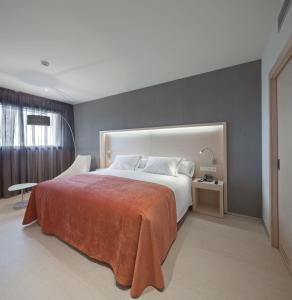 um quarto com uma cama grande e um cobertor laranja em Sercotel Hola Tafalla em Tafalla
