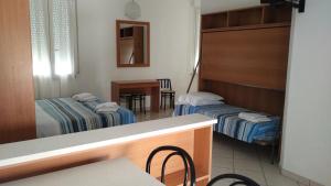 a room with two beds and a table and a mirror at B&B Residence Sorriso in Cattolica