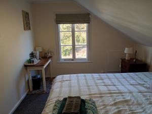 a bedroom with a bed and a desk and a window at Western House B&B Kurow in Kurow