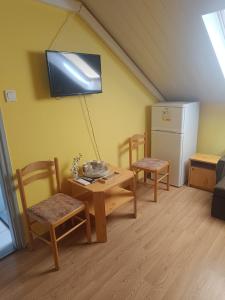a living room with a table and chairs and a refrigerator at Király Szálló in Nagykanizsa