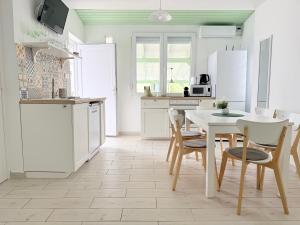 a kitchen with white cabinets and a table and chairs at Helló Zsóry Apartman in Mezőkövesd +19 photos