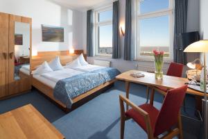 a hotel room with a bed and a desk and a desk at Hotel Haus Margarete am Meer in Norderney