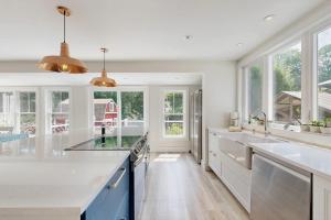 a kitchen with white counters and blue cabinets and windows at Salt Air Serenity in Old Orchard Beach +45 photos