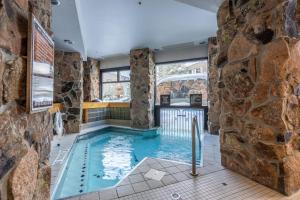 a pool in a room with a stone wall at Shoshone 1909 in Big Sky