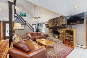 a living room with a leather couch and a stone fireplace at Peaceful Home in North Conway