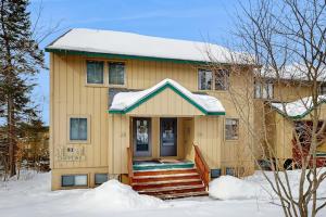 a yellow house with snow on the front of it at Mad House in Waterville Valley
