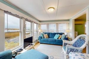 a living room with a blue couch and some windows at The Eastern Avenue Cottage in Wells Beach