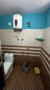 a bathroom with a toilet with a air conditioner on the wall at Khushraali hotel and restaurant in Rudraprayāg