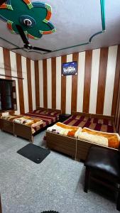 three beds in a room with a striped wall at Khushraali hotel and restaurant in Rudraprayāg