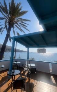a balcony with tables and chairs and a palm tree at Tony's Rooms in Alinda