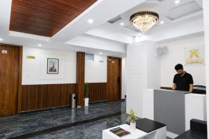 a man standing at a counter in a lobby at Xenious Smart Suites Greater Noida in Noida